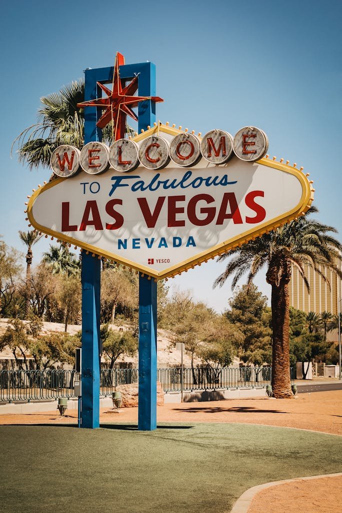 Famous Welcome to Las Vegas sign with palm trees under clear blue sky.